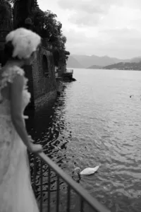 Black and white image of model overlooking Lake Como with swan in water creating artistic editorial moment