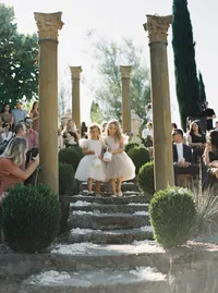Flower girls walking down stone steps tossing petals during a romantic outdoor ceremony at a Lake Oswego Oregon winery wedding.