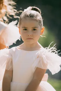 Flower girl portrait wearing a blush pink dress with feather details during a romantic Lake Oswego Oregon garden wedding.