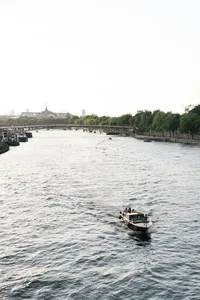 Wide view of a boat on the Seine River with the Paris skyline in the distance
