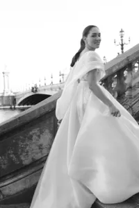 Bride walking through Paris in a flowing couture gown with soft movement, captured against historic architecture.