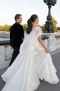 Bride and groom walking hand in hand across the Pont Alexandre III bridge with the bride’s flowing gown moving in the wind.