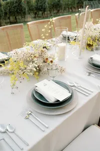 Side angle view of ceremony table settings with organic centerpieces and layered place settings.