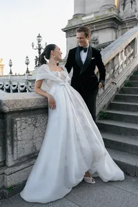 Bride and groom laughing together on the Pont Alexandre III bridge with Paris architecture in the background.
