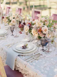 Place setting with blush florals, brass flatware and smoky glassware at vineyard wedding.