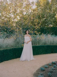 Bride in a flowing tulle gown standing along a manicured hedge path, a serene garden moment from a Santa Barbara wedding editorial by Yuliya Supin Design