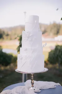 Elegant custom wedding cake decorated with delicate sugar flowers displayed on dusty blue linen and silk overlay during a romantic winery wedding in Lake Oswego Oregon.