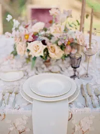 Place setting with blush florals, brass flatware and smoky glassware at vineyard wedding.