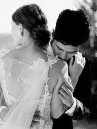 Groom kissing bride’s shoulder in black and white portrait at Sunstone Winery wedding in Santa Ynez.