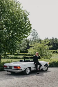 Groom posing beside classic car at private estate wedding in Vancouver, Washington.