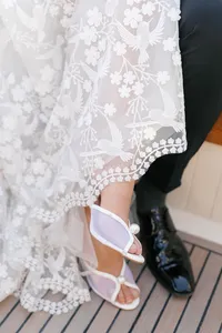 Close detail of the bride and groom’s shoes and the embroidered wedding gown captured inside a boat on the Seine River in Paris.