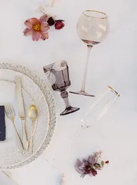 Elegant table setting with glassware, plates and florals at vineyard wedding reception.