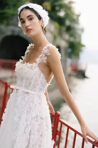 Model in textured lace gown standing by red railing at Villa Cipressi overlooking Lake Como