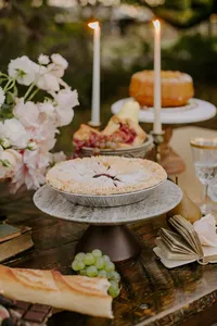 Wedding dessert table with pies, candles, and fruit styling in garden reception