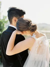 Romantic portrait of bride resting on groom’s shoulder during vineyard wedding in Santa Ynez Valley.