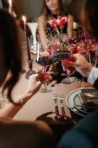 Guests toasting with wine during a rehearsal dinner celebration inside the Lucid Wild Estate winery cellar.