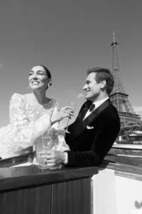 Bride and groom toasting with champagne on the boat, the Eiffel Tower behind them