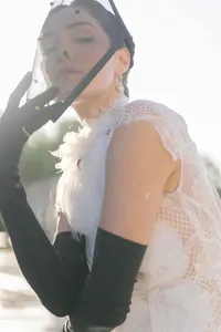 Close-up fashion portrait highlighting lace textures, black gloves, and a polka-dot headpiece on a couture bridal gown in Paris.