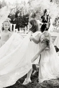 Emotional black and white moment of flower girls helping the bride carry her wedding gown during a romantic garden wedding in Lake Oswego Oregon.
