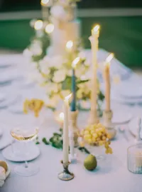 Reception tablescape with taper candles, grapes, pears, and trailing greenery, an old-world European detail from a Santa Barbara wedding editorial by Yuliya Supin Design