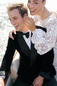 Close portrait of the bride and groom laughing together on the boat, the bride's sheer lace sleeve visible