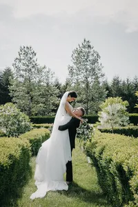 Groom lifting bride during private estate wedding in Vancouver, Washington surrounded by garden landscape.