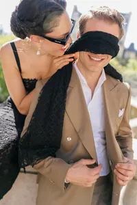 Bride playfully covering the groom’s eyes with her silk scarf as they laugh together during their Paris engagement session.