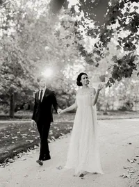 Black-and-white portrait of bride and groom walking hand in hand across a leaf-scattered path, from a Santa Barbara wedding editorial by Yuliya Supin Design
