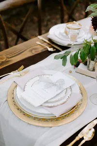 Luxury wedding place setting with antique plates, linen, and stationery on outdoor reception table