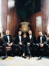 Groom and groomsmen sitting together in an elegant hotel lounge before the celebration during a Lake Oswego Oregon winery wedding.