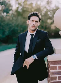 Groom leaning against a stone ledge, his tuxedo and wristwatch in focus, a refined detail from a Santa Barbara wedding editorial by Yuliya Supin Design