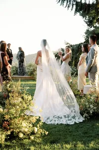 Bride walking toward her groom across a ceremony island surrounded by tall wild yellow florals at Lucid Wild Vineyard in Oregon.