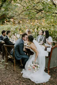 Wedding guests and couple cheering at outdoor reception table in garden setting