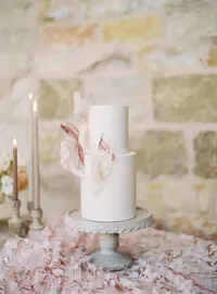 Wedding cake styled with candles and silk floral linen at Sunstone Winery reception.
