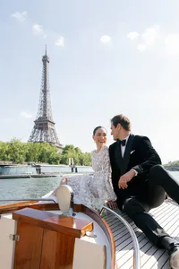 Bride and groom laughing together at the bow of the boat with the Eiffel Tower in the background