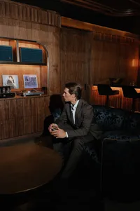 Groom seated in an intimate speakeasy-style room during rehearsal dinner, waiting for his bride.