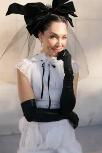 Close portrait of a bride in Paris wearing a couture wedding gown with black gloves and a sheer veil headpiece with a statement bow, styled in a refined editorial bridal look.