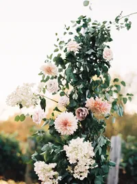 Romantic ceremony arch filled with garden roses and lush greenery during an outdoor winery wedding ceremony in Lake Oswego Oregon.