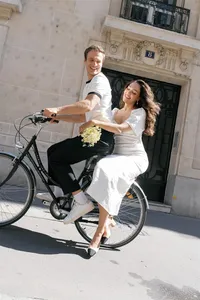 Couple laughing as they ride a bicycle through a city street