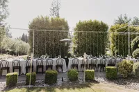 Outdoor reception with half arch structure, black chairs, and ivory velvet linens at private estate wedding in Vancouver, Washington.