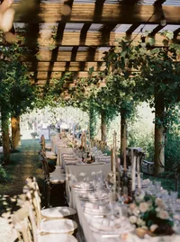 Long reception tables styled under a vine-covered tent with romantic florals and candlelight at a Lake Oswego Oregon winery wedding.