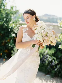 Bride holding bouquet with wind blowing silk ribbon at Sunstone Winery wedding.