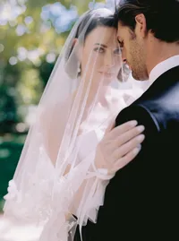 Close-up of the bride's lace glove and tulle veil against the groom's dark suit, a delicate texture detail from a Santa Barbara wedding editorial by Yuliya Supin Design