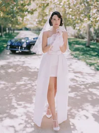 Bride in a short white dress and heels, dappled sunlight falling across the path, from a Santa Barbara wedding editorial by Yuliya Supin Design