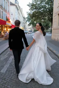Bride and groom standing together in the middle of a Paris street surrounded by historic architecture and glowing evening lights.