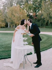 Bride and groom approaching a champagne coupe tower staged on the lawn, from a Santa Barbara wedding editorial by Yuliya Supin Design