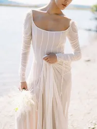Bridal editorial dress detail with soft feather bouquet in natural outdoor setting
