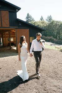 Bride and groom walking hand in hand outside the estate bar at sunset.