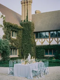 Reception table with the wedding cake as centerpiece, set on the lawn before an ivy-covered estate, from a Santa Barbara wedding editorial by Yuliya Supin Design