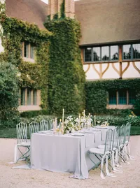 Long reception table set with candlelight and florals against the stone estate facade, styled for a Santa Barbara wedding editorial by Yuliya Supin Design